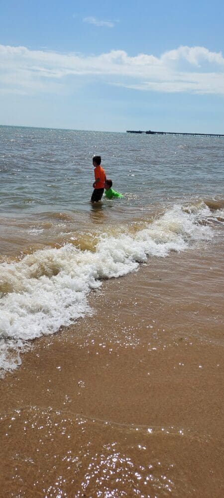Two boys wading in the sea during a coach trip to the beach