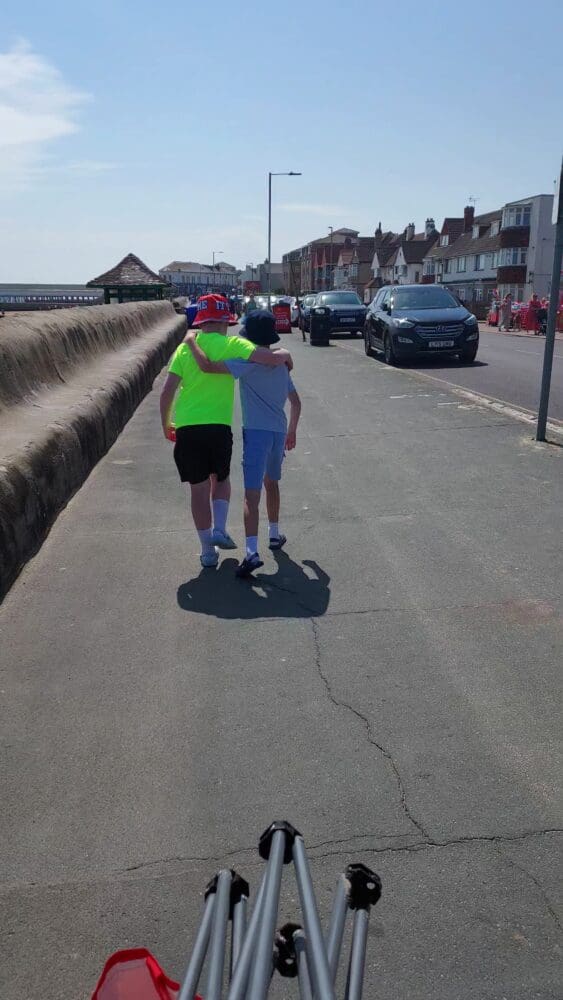 Two people walking arm in arm along a seafront promenade