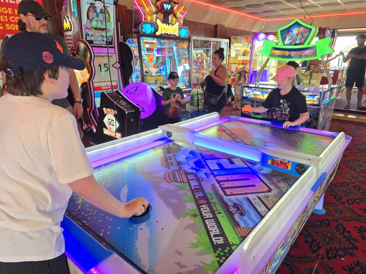 Group playing air hockey together at a seaside arcade
