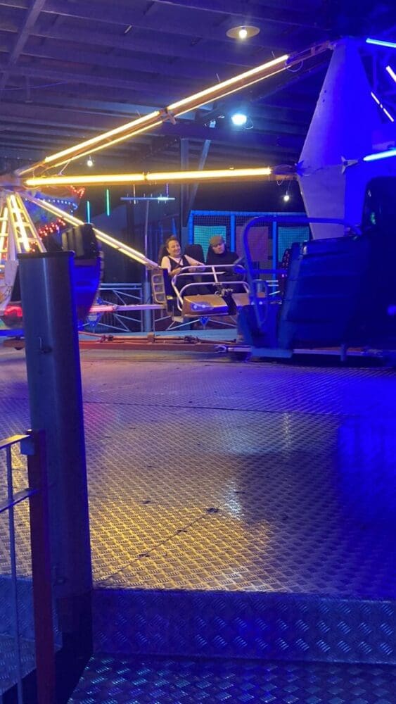 Riders enjoying an illuminated fairground ride at night