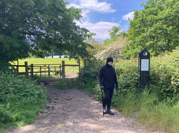 Man standing by a farm gate on a countryside nature trail