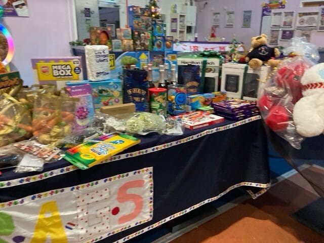 Table of Christmas raffle prizes including sweets, toys and a teddy bear