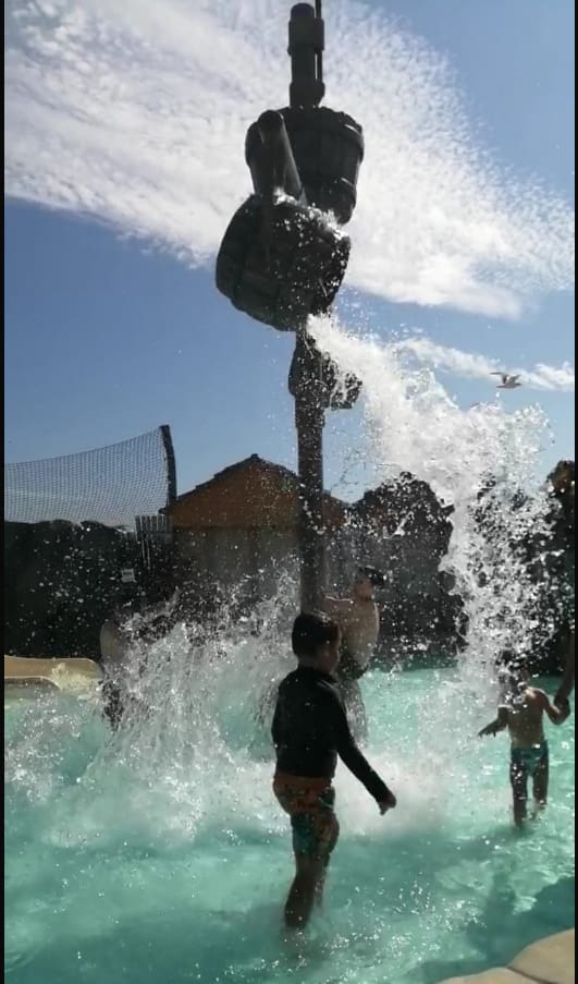 Child splashing in a water park fountain feature, 2024