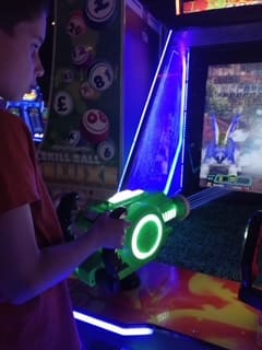 Boy playing a light gun arcade game at an amusement centre