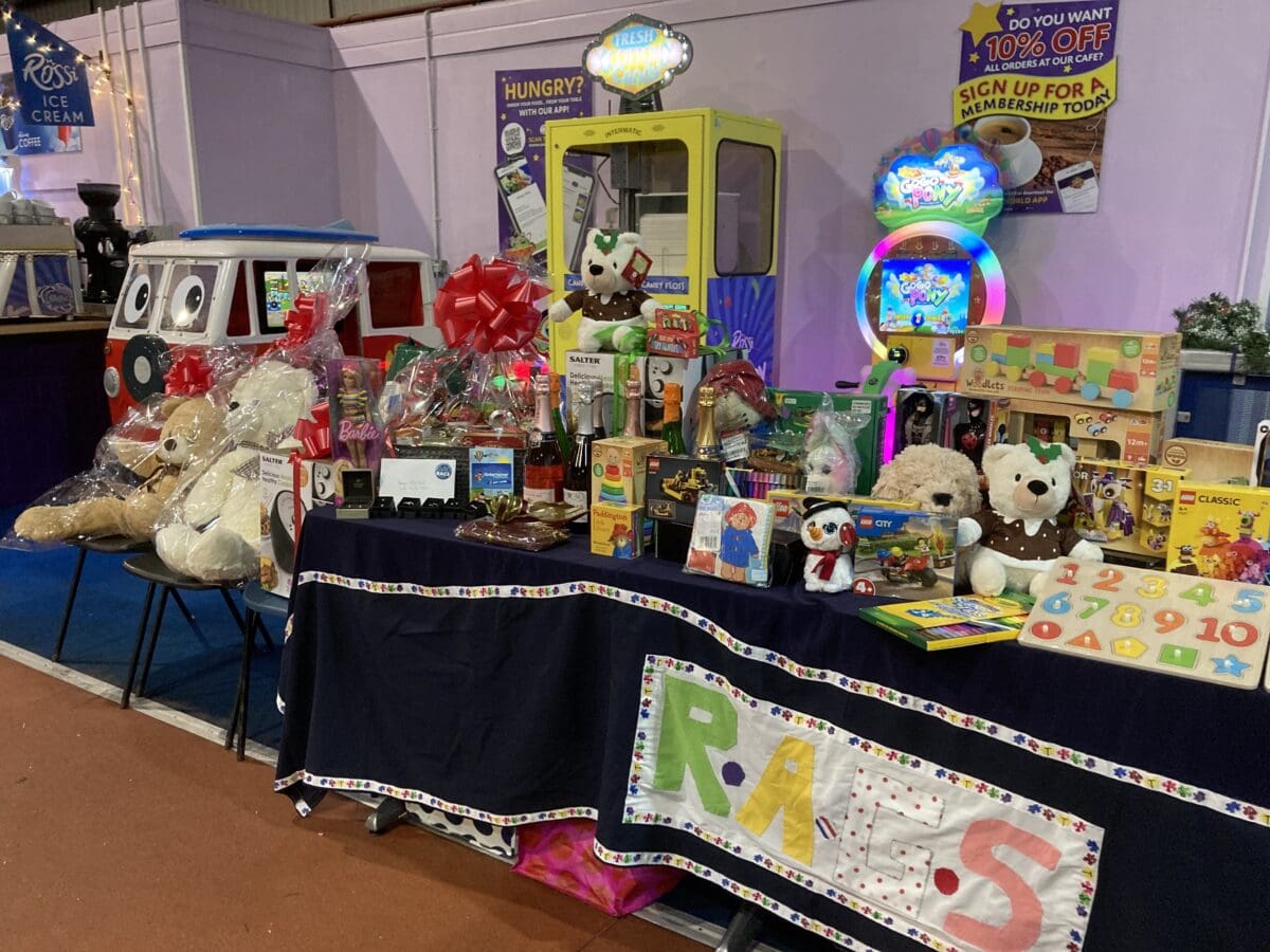 Raffle prize table with a toy camper van and teddy bears at a RAGS event
