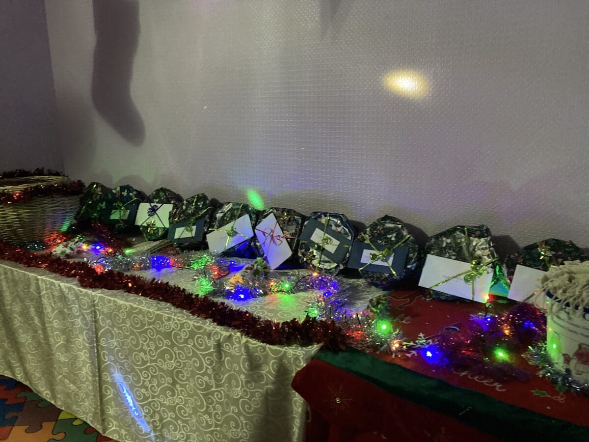 Row of wrapped Christmas raffle gifts decorated with fairy lights and tinsel