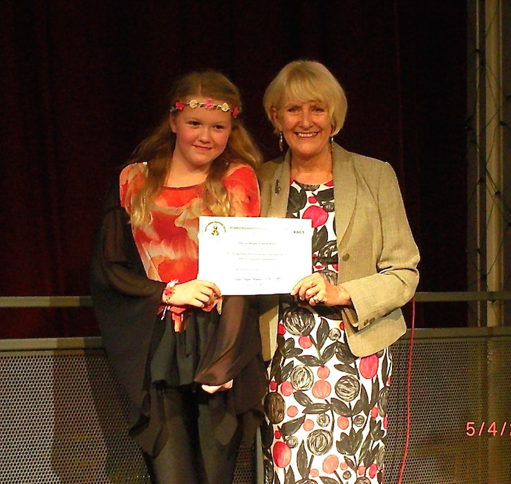 Girl receiving a certificate from a RAGS presenter on stage, 2014