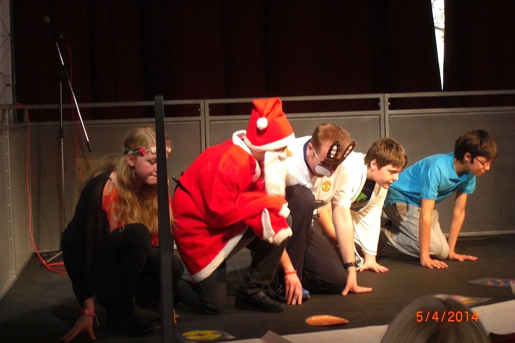 Children in fancy dress kneeling on stage for a RAGS drama game, 2014