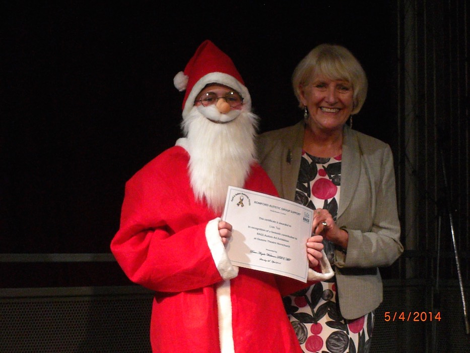 Child dressed as Santa receiving a RAGS certificate award, 2014