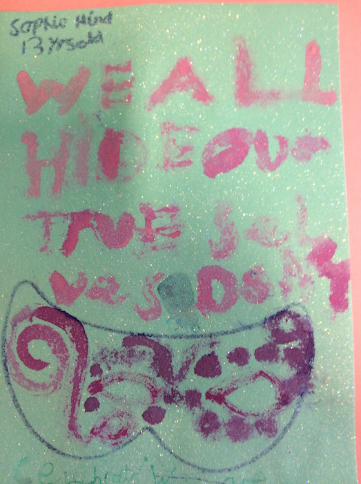 Child's glitter artwork with a masquerade mask design and handwritten text