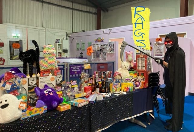 Halloween-themed raffle stall with a Grim Reaper costume at a RAGS event