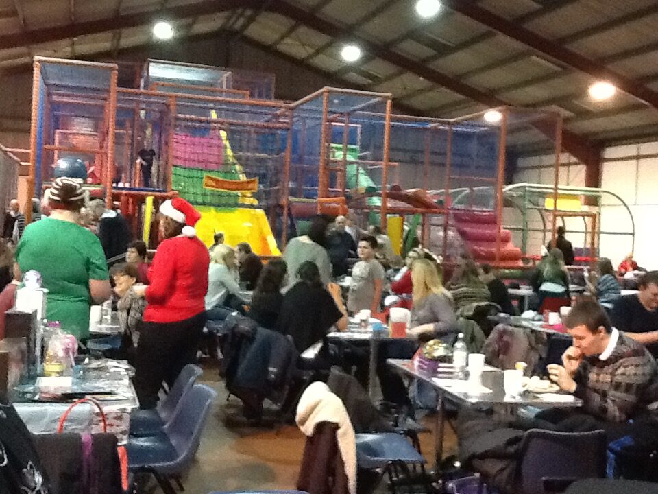 Families seated at tables in soft play centre for RAGS Christmas party