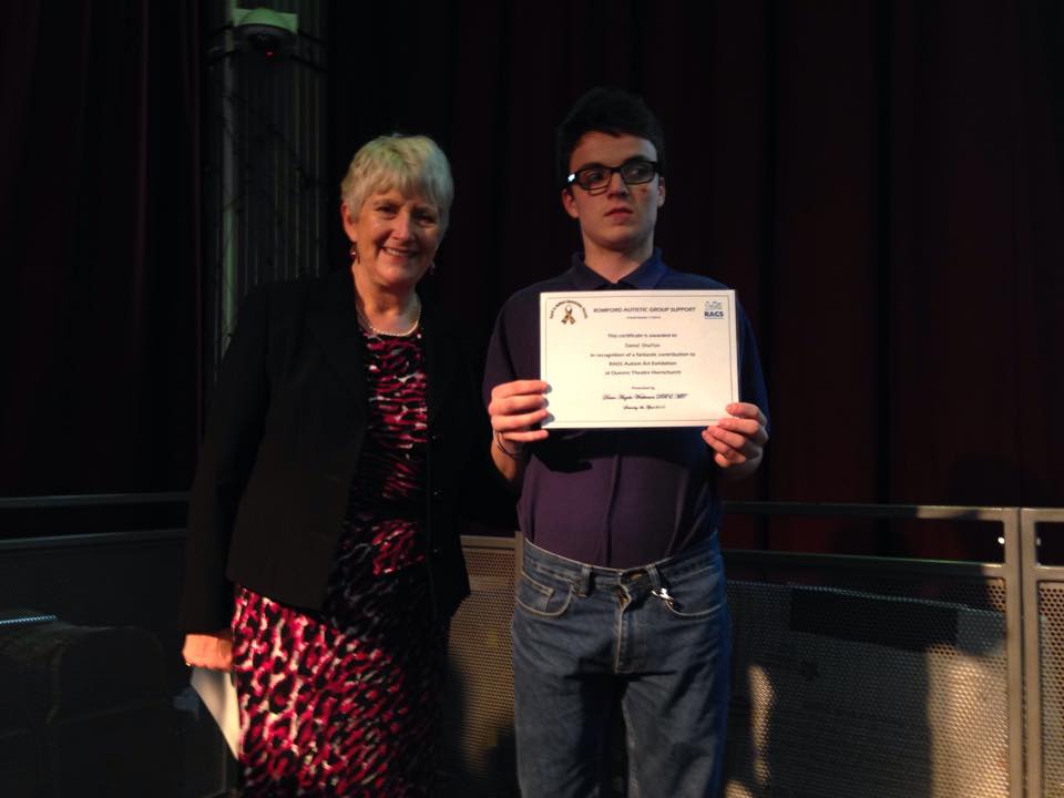 Young man holding his RAGS Autism Art Exhibition certificate with the Mayor