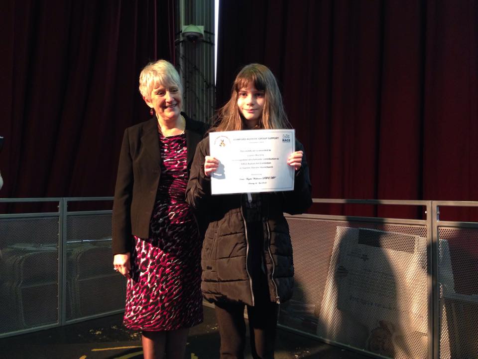 Girl holding her RAGS Autism Art Exhibition certificate with the Mayor