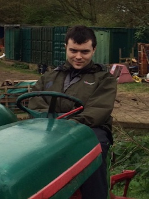 Young man sitting on a ride-on tractor at a farm visit, 2014