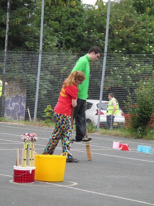 Circus skills workshop with a performer helping a man balance on a beam, 2014