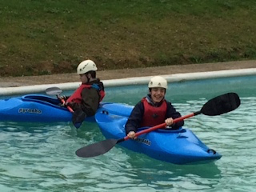 Two boys smiling in kayaks with paddles at a water sports centre, 2014