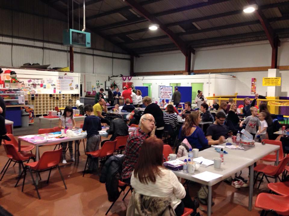 Families seated at tables during a RAGS Christmas party at a soft play centre