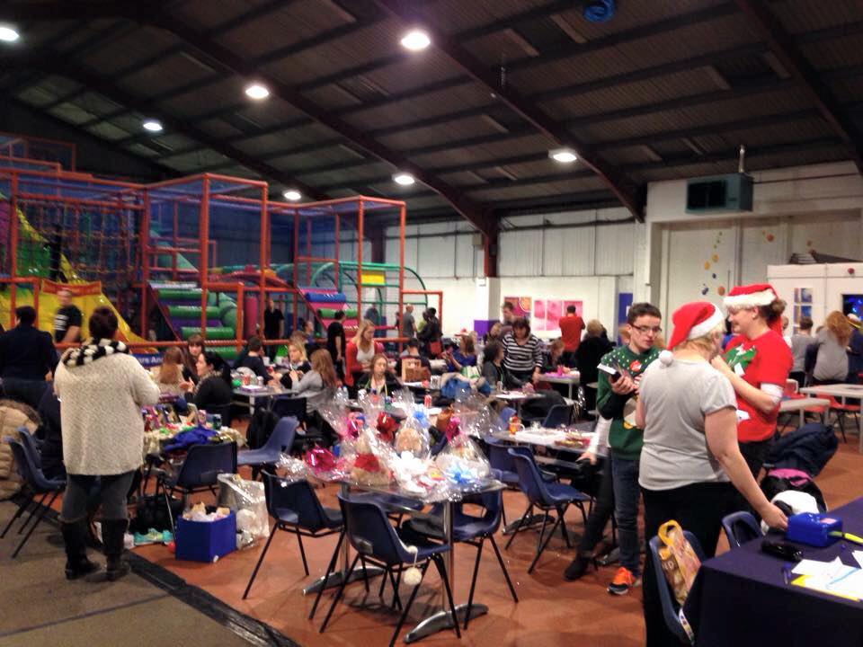 Wrapped raffle prizes on tables at a RAGS Christmas party, staff in Santa hats