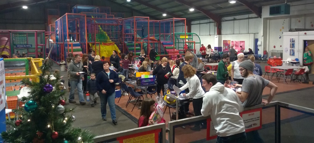 Wide view of families and a Christmas tree at a RAGS soft play party